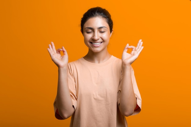 Portrait of young adult indian woman in sari meditating zen like with ok sign mudra gesture