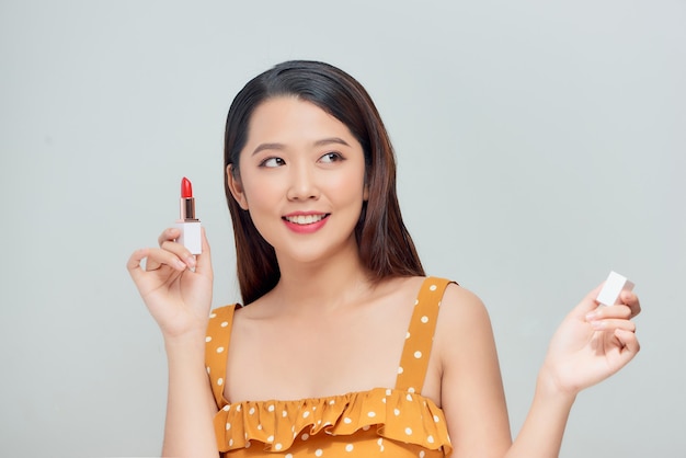 Portrait of a young adult woman applying makeup on her face