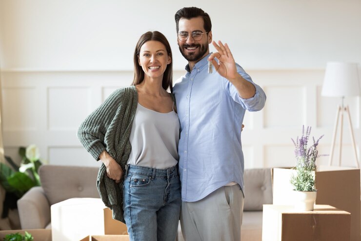 眼鏡をかぶった幸せな男が新しいアパートに引っ越すことに興奮した美しい妻を抱きしめる 笑顔の不動産に満足した家主の肖像画