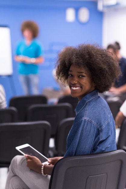 portrait of young African American business woman at modern startup office interior, team in meeting in background