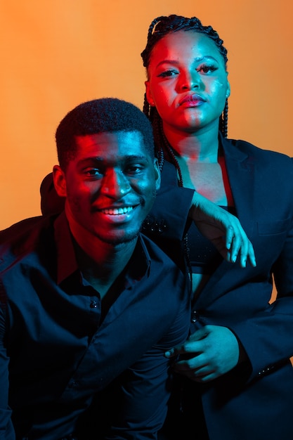 Portrait of young african american couple in love posing at  dressed in classic clothes. Neon