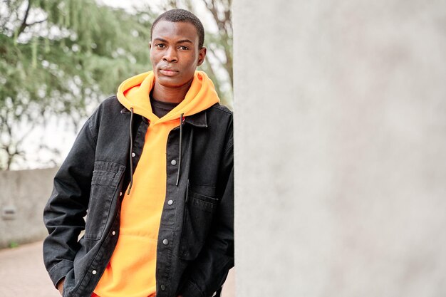 Portrait of young african american man standing outside by white wall in a city Copy space for text