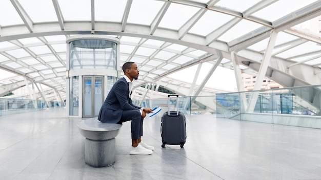 Portrait Of Young African American Man Waiting with Suitcase At Airport