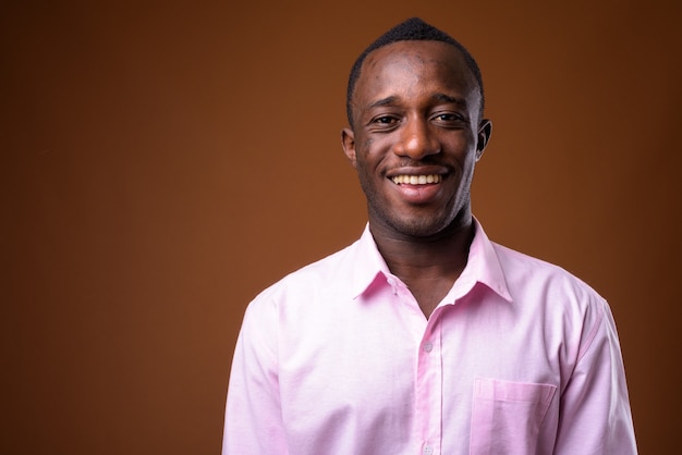 Портрет молодого африканского бизнесмена, улыбающегося коричневой стене