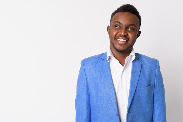 Portrait of young African businessman wearing blue suit against white wall