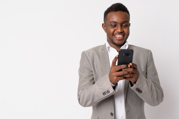 Portrait of young African businessman wearing suit against white wall