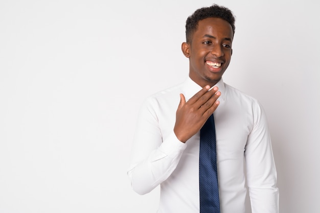 Portrait of young African businessman with Afro hair against white wall