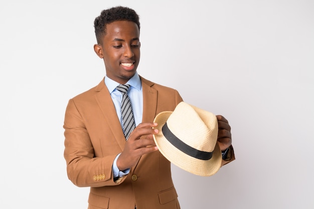 Portrait of young African businessman with Afro hair in brown suit against white wall