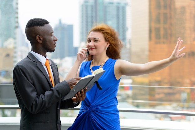 Portrait of young African businessman and young businesswoman with red hair together