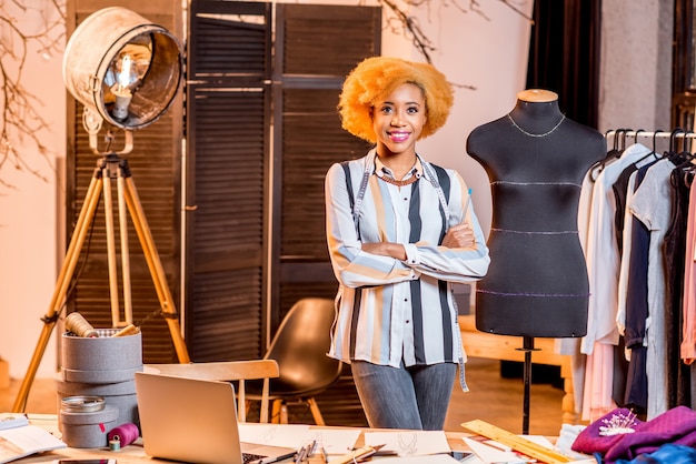 Portrait of a young african fashion designer standing near the mannequin at the studio