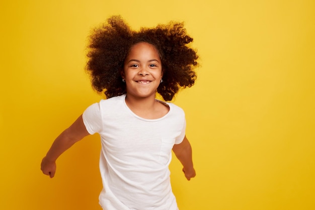 きれいな黄色の背景に笑顔と喜びの若いアフリカの女の子の肖像画