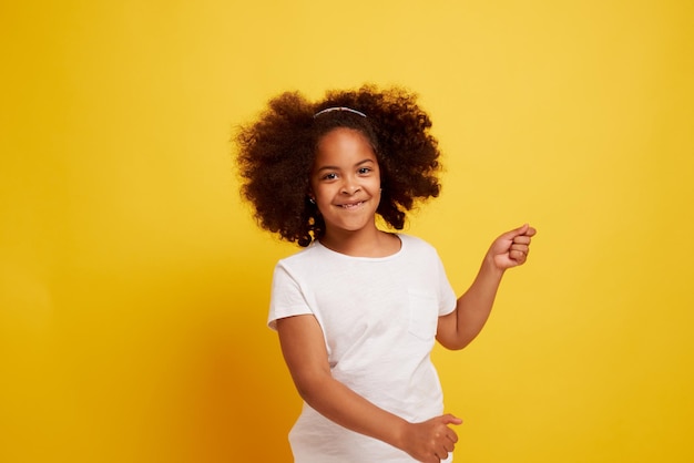 Portrait of a young african girl smiling and rejoicing on a clean yellow background