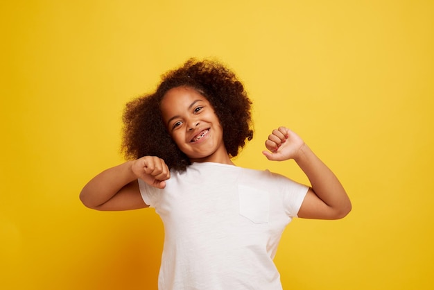 きれいな黄色の背景に笑顔と喜びの若いアフリカの女の子の肖像画