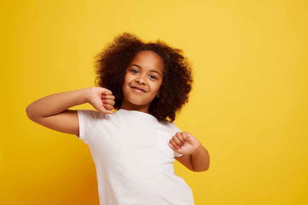 きれいな黄色の背景に笑顔と喜びの若いアフリカの女の子の肖像画