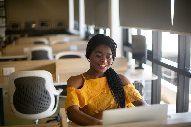 Portrait of a young African girl working at a laptop in a cafe during a coffee break A break relax