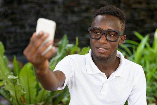 Portrait of young African man against view of the garden in nature outdoors