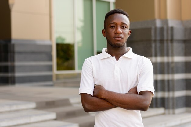 Portrait of young African man at modern building in the city outdoors