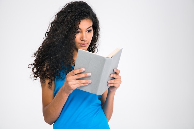 Portrait of a young afro american woman reading book isolated on a white wall