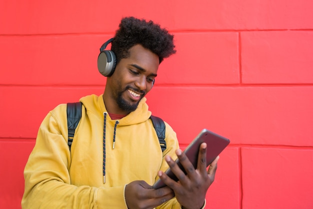 Portrait of young afro man using his digital tablet with headphones