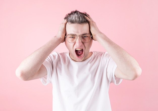 Portrait of young angry man with tongue piercing wearing eyeglasses and white t shirt