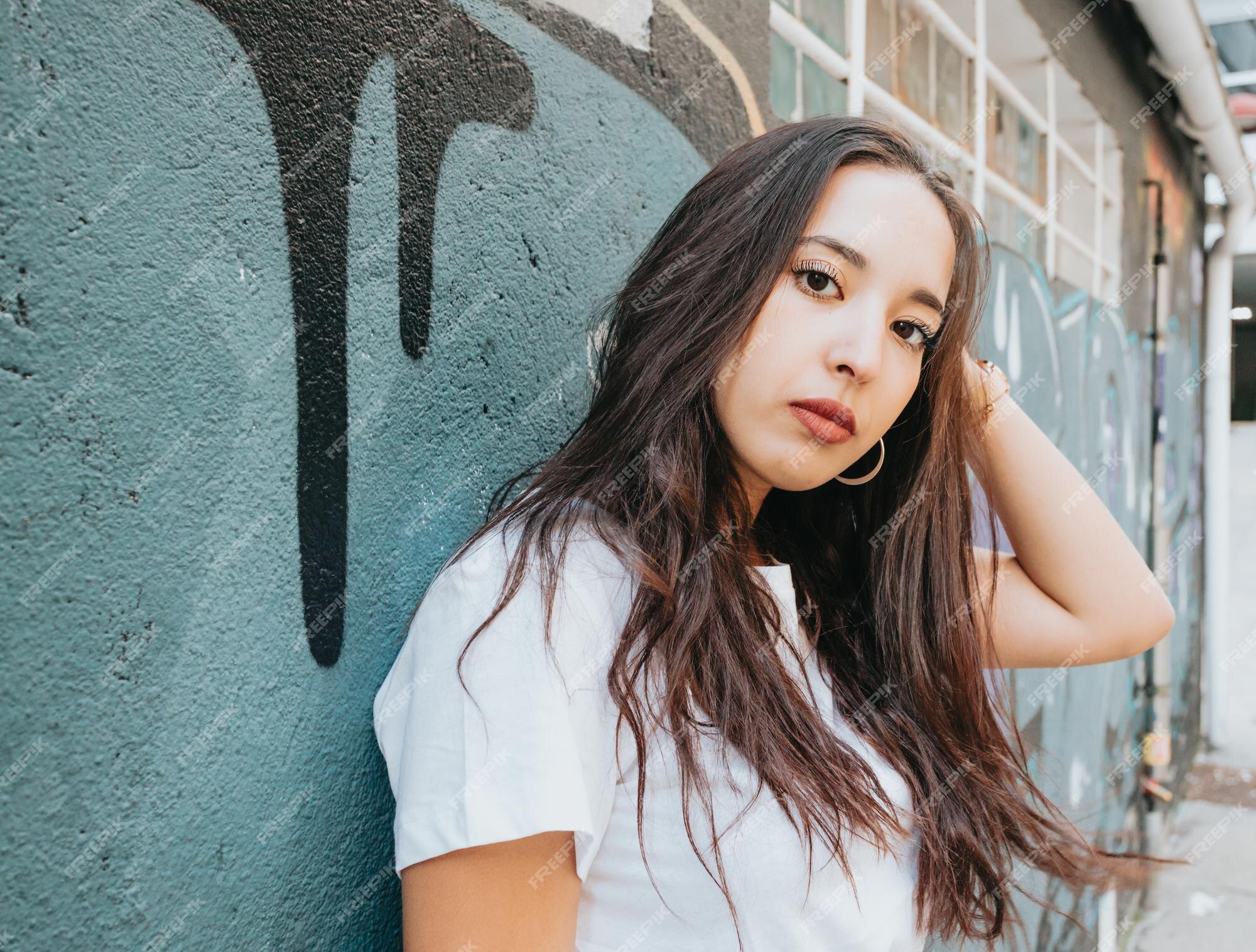 Premium Photo | Portrait of a young arab african girl on serious hip hop  youngster attitude looking serious to camera on a white shirt with a  graffiti background. beauty young street life