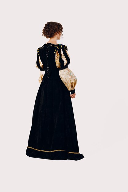 Portrait of a young aristocratic woman dressed in a medieval dress on white background back view