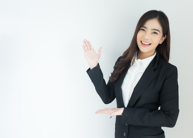 Portrait of young asian business woman pointing up over white background.