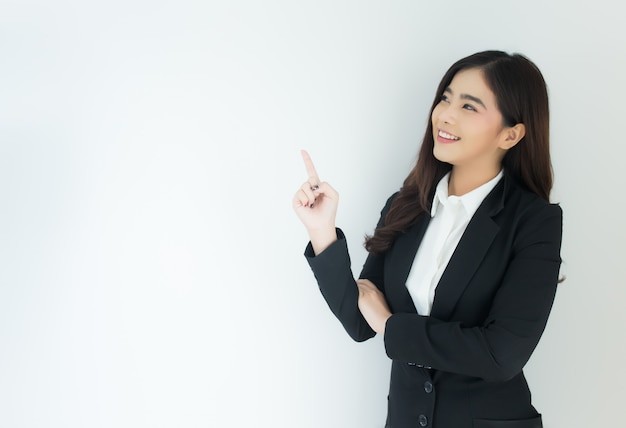 Portrait of young asian business woman pointing up over white background.