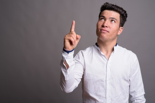 Portrait of young Asian businessman against gray wall