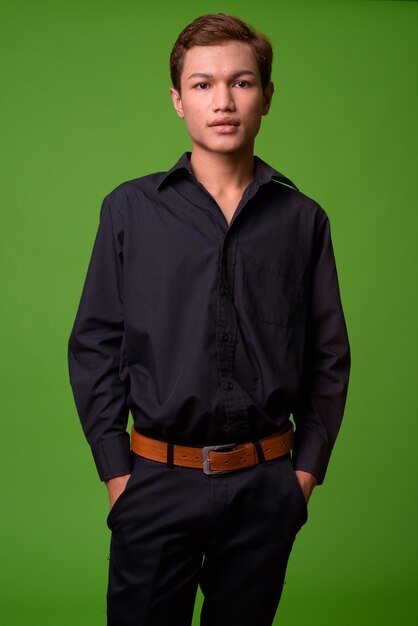 Портрет молодого азиатского бизнесмена против зеленой стены