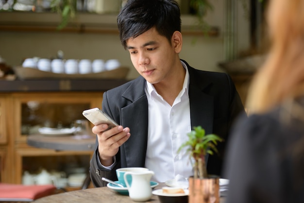 Portrait of young Asian businessman and young Asian businesswoman together relaxing at the coffee shop