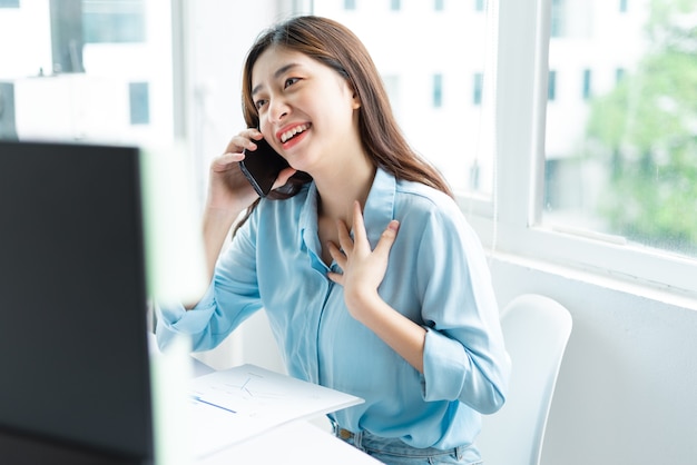 Portrait of young asian businesswoman happily talking on the phone