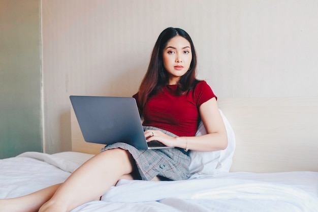 Portrait of a young Asian businesswoman working from home looking at laptop screen indoors