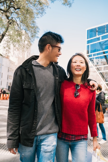 Portrait of young Asian couple in love walking in the city after shopping. Shop concept.