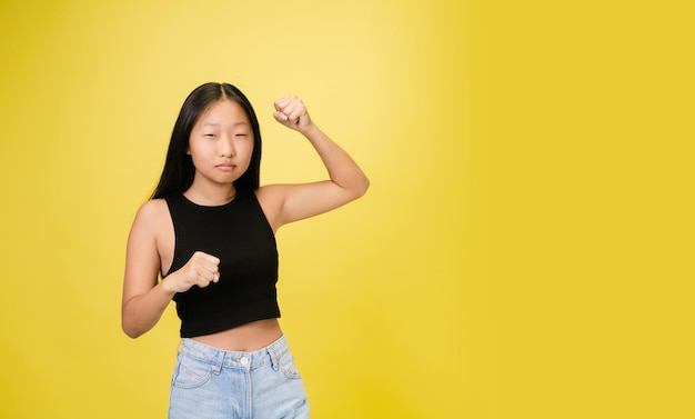 Portrait of young asian girl isolated on yellow studio background