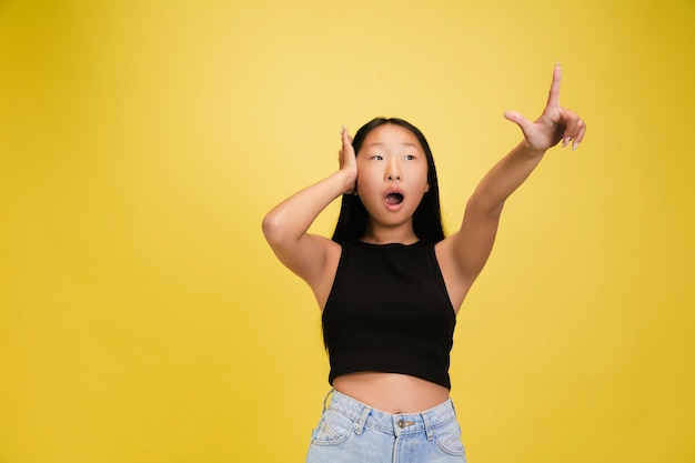 Portrait of young asian girl isolated on yellow studio background