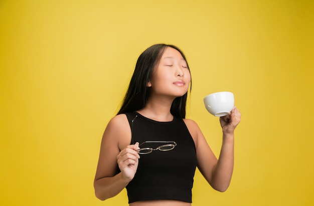 Portrait of young asian girl isolated on yellow