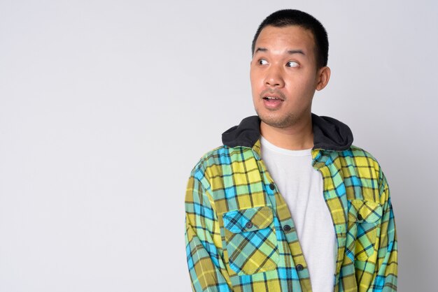 Portrait of young Asian hipster man wearing hoodie against white wall