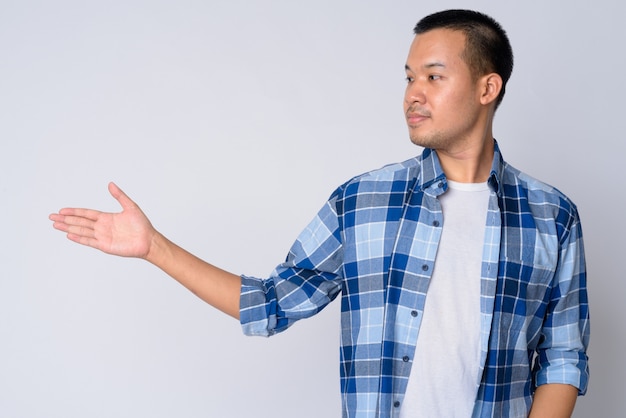 Portrait of young Asian hipster man with short hair against white wall