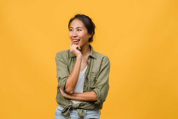 Portrait of young asian lady with positive expression, arm crossed, smile broadly, dressed in casual cloth over yellow wall. happy adorable glad woman rejoices success. facial expression concept