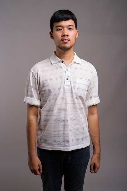 Portrait of young Asian man against gray