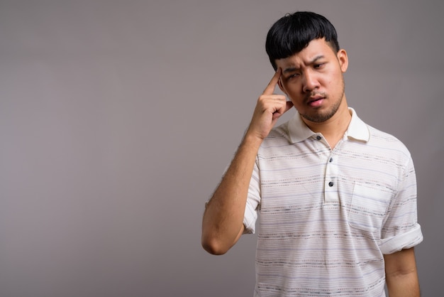 Portrait of young Asian man against gray