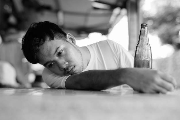 Portrait of young Asian man getting drunk in the streets outdoors