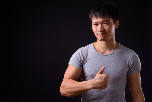 Portrait of young Asian man giving thumbs up