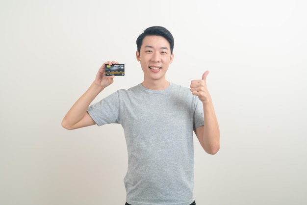 白い背景の上のクレジットカードを保持している肖像画の若いアジア人