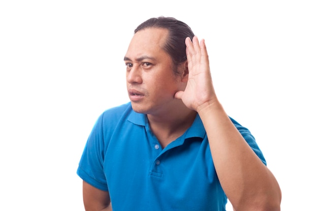 Portrait of young Asian man listening carefully gesture one hand on ear gossip rumors secret concept