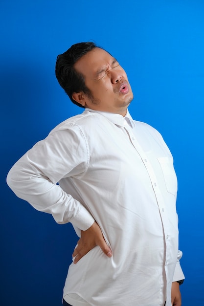 Portrait of young Asian man looked tired and suffer from back pain after working for too long