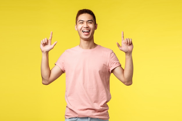 Портрет молодого азиатского человека показывая жест над желтой стеной