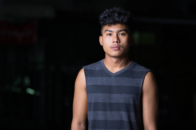 Portrait of young Asian man in the street at night outdoors