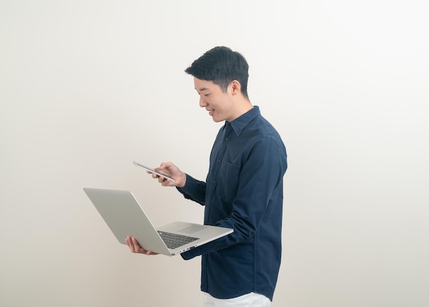 портрет молодой азиатский мужчина разговаривает смартфон или мобильный телефон и рука держит ноутбук на белом фоне